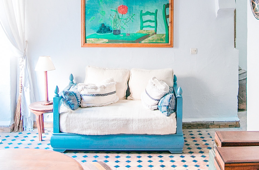 Cyan poster-style day bed with creme cushions and duvet in bright room with diamond-patterned floor.