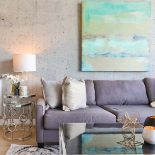 Living room with beige couch, large lamp, abstract painting in pastel colours, glass table with star sculpture on top of it.